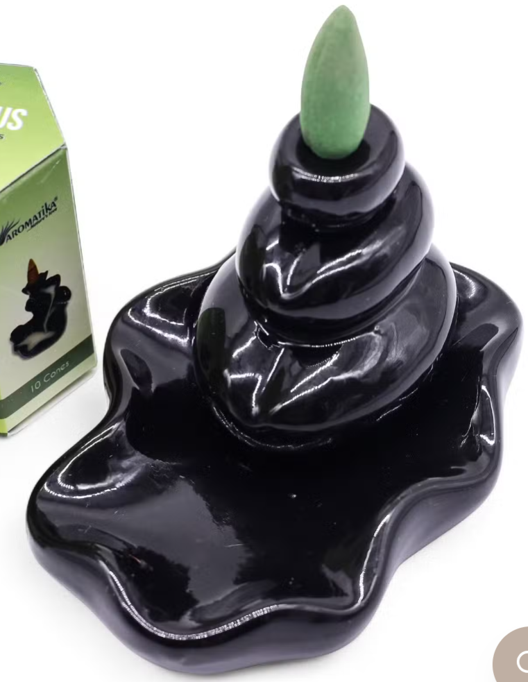 A glossy black ceramic incense burner with a wavy base and three stacked incense sticks, shown next to its green packaging box on a white background.