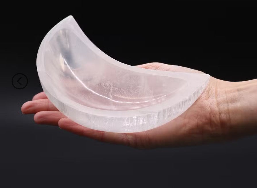 A translucent crescent-shaped silicone or plastic insert held in a person's hand against a dark background.