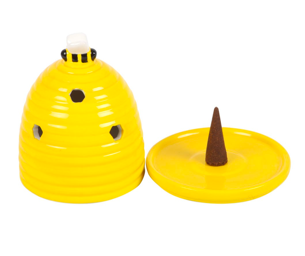 Yellow beehive-shaped incense holder with ventilation holes, shown with its lid off and a brown incense cone standing in the center of the round base, on a white background.