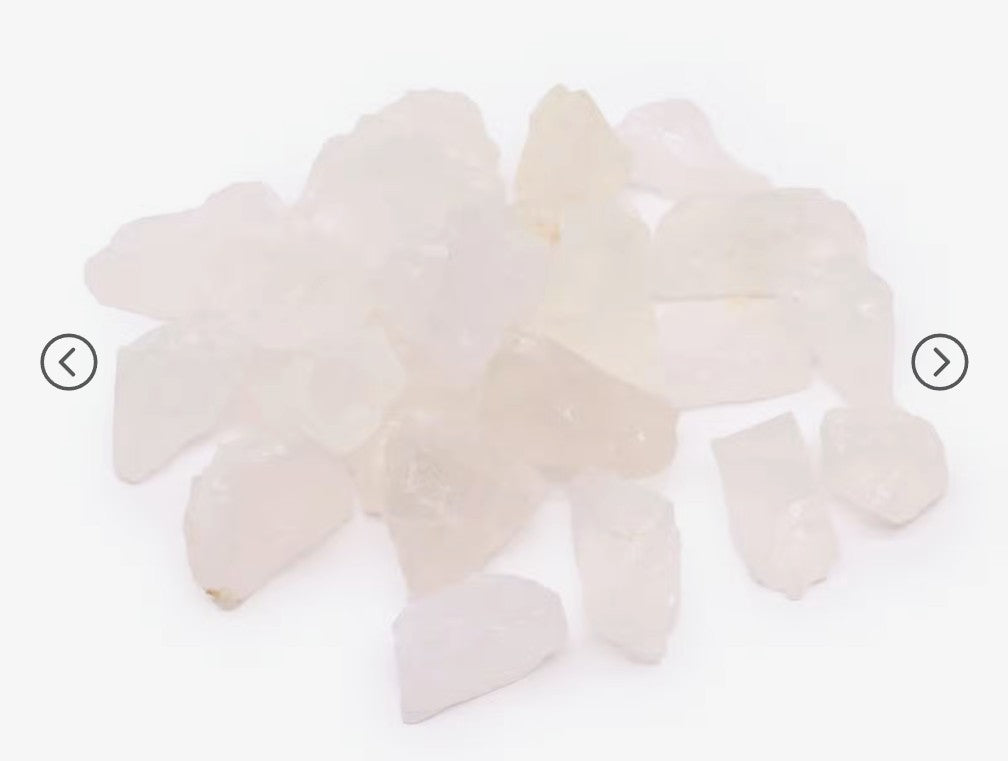A pile of raw rose quartz crystal chips on a plain white background.