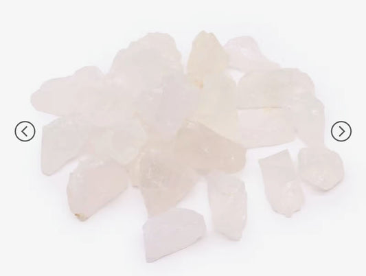 A pile of raw rose quartz crystal chips on a plain white background.