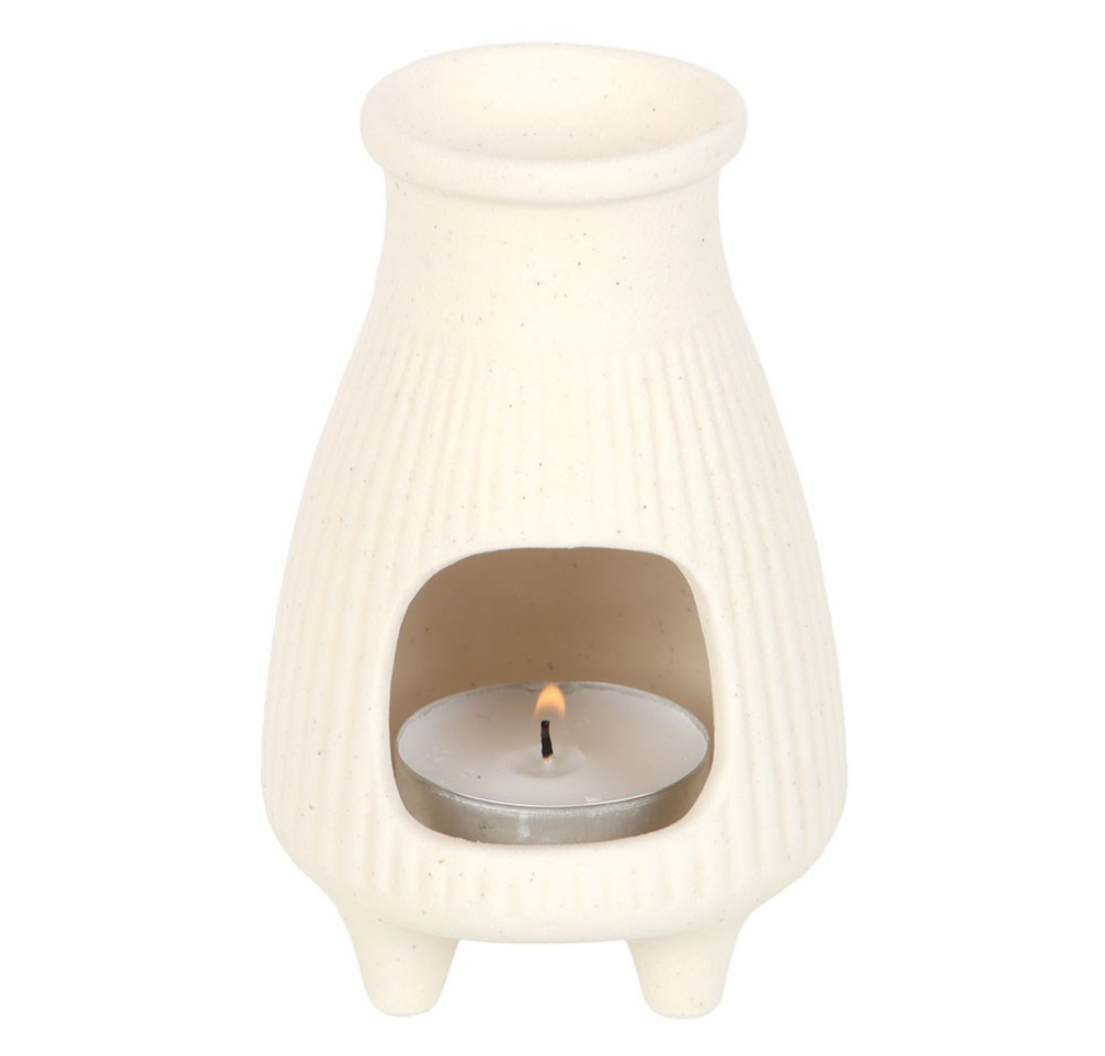 White ceramic oil burner with a lit tealight candle on a white background