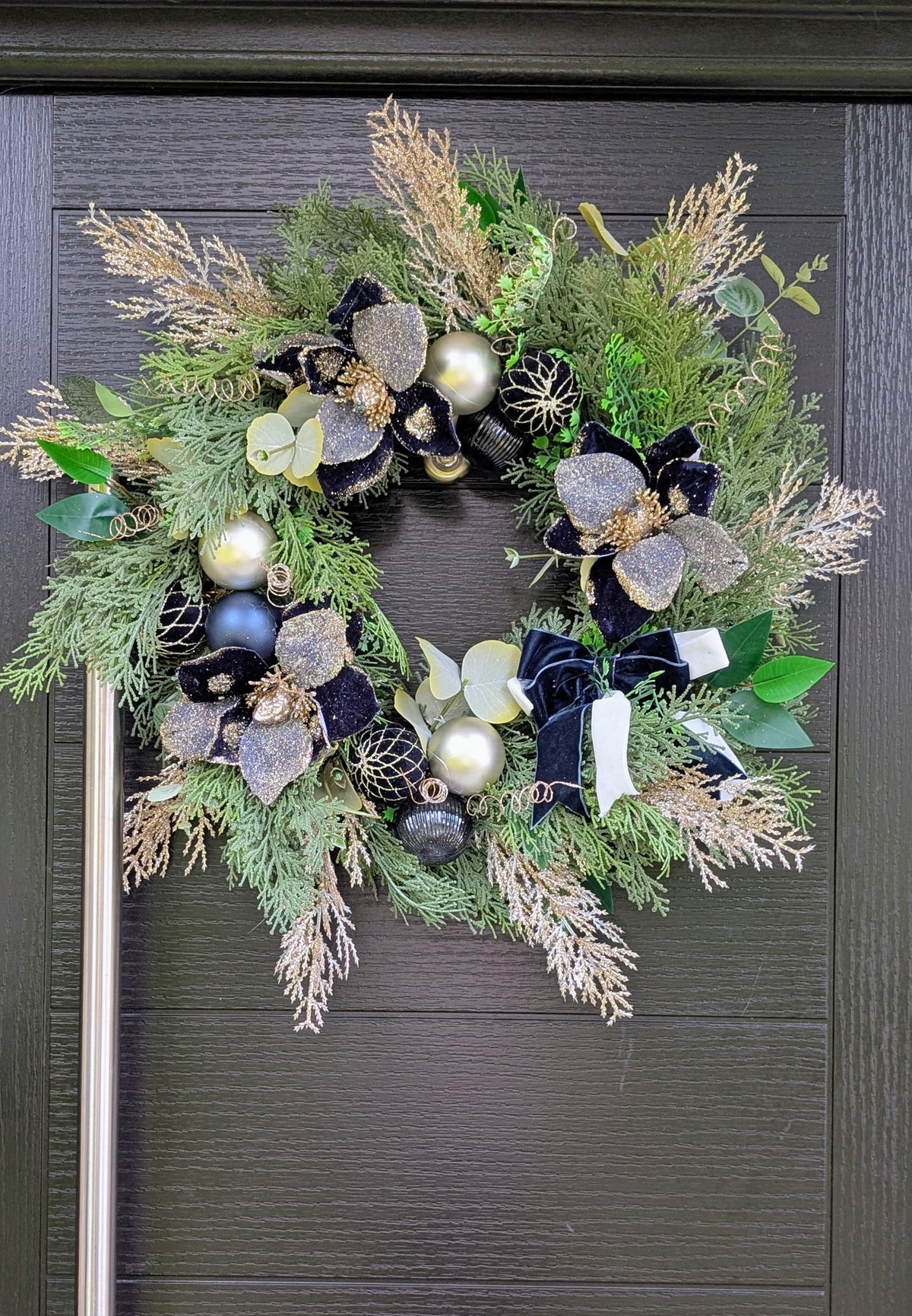 Luxury handmade navy and champagne Christmas wreath with velvet flowers, sparkling foliage, baubles and navy and ivory ribbon bow.