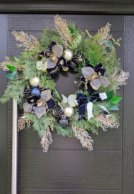 Luxury handmade navy and champagne Christmas wreath with velvet flowers, sparkling foliage, baubles and navy and ivory ribbon bow.