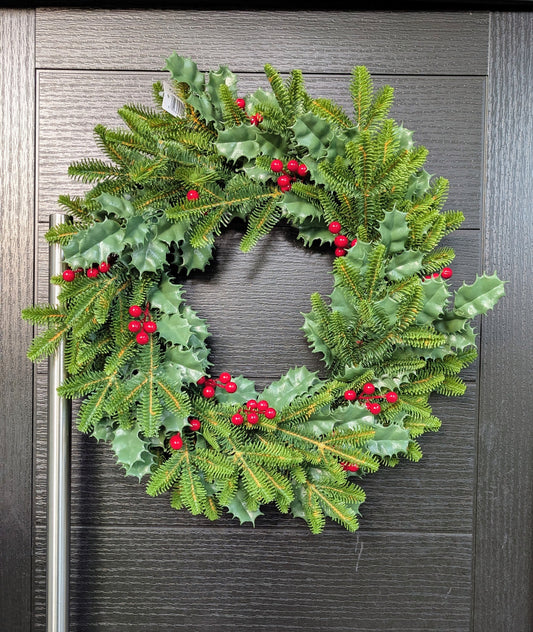 Approximate 60cm traditional Christmas wreath with green spruce foliage, glossy holly leaves and bright red berries displayed on a dark front door.