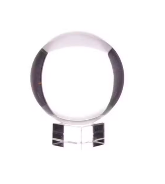 A clear glass crystal sphere on a matching clear acrylic stand, photographed against a solid white background.